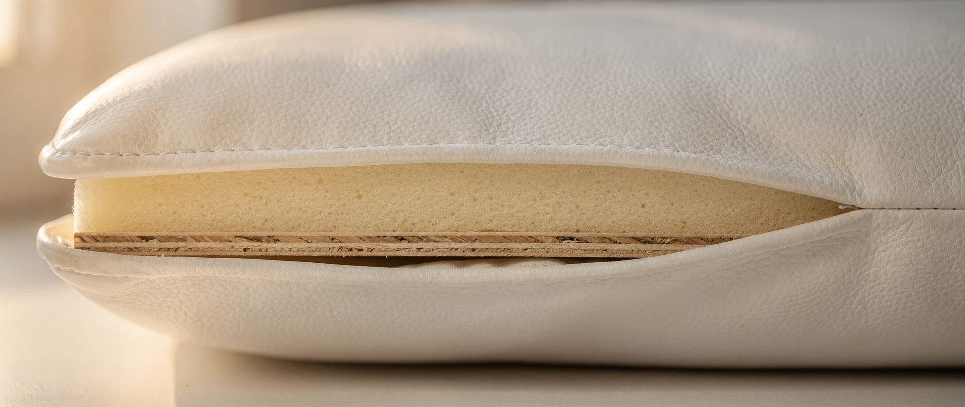 Coupe d'un coussin : mousse crème haute densité, bord de contreplaqué et housse en vinyle marin blanc.