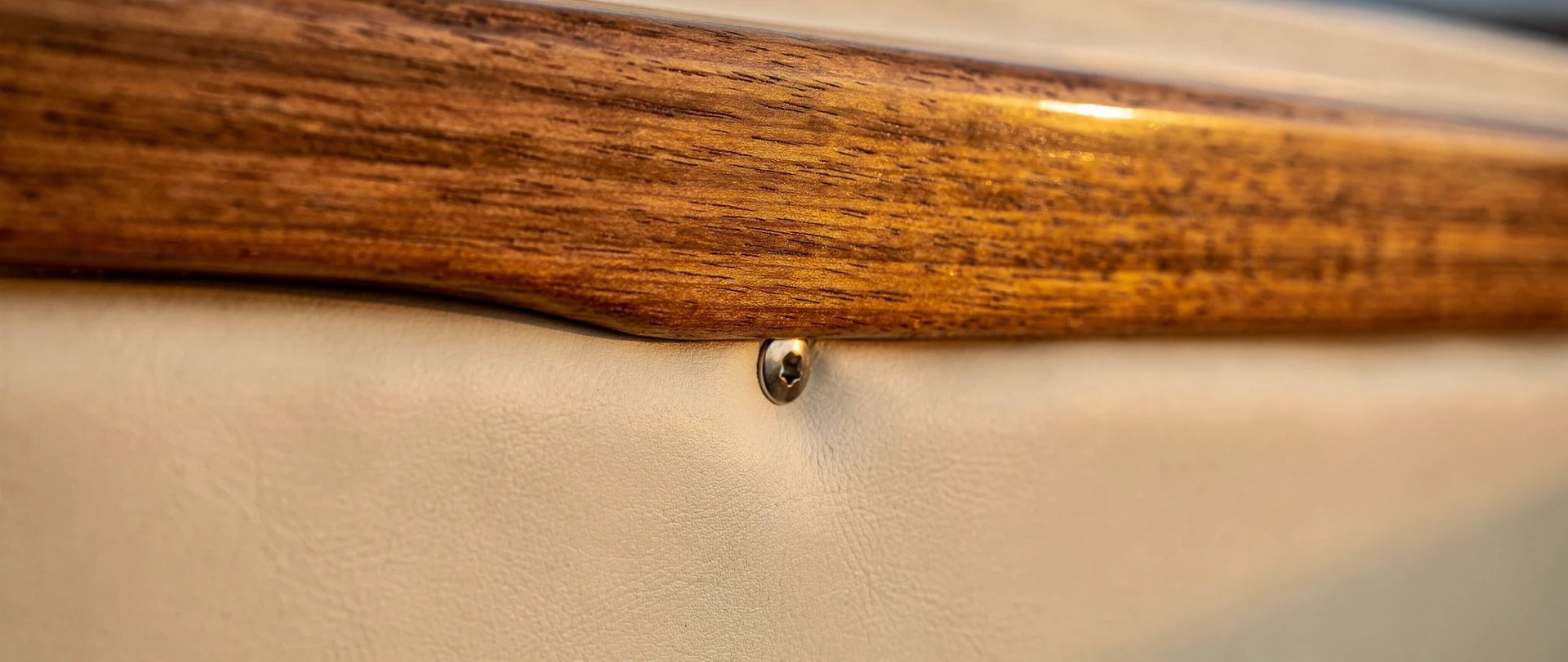 Bordure de teck chaud contre un coussin de vinyle marin crème, avec une vis en acier inoxydable.