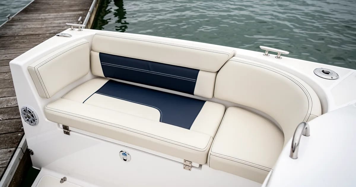 Coussins neufs crème et marine installés dans le cockpit d'un bateau au quai, résultat d'un projet de rembourrage sur mesure.